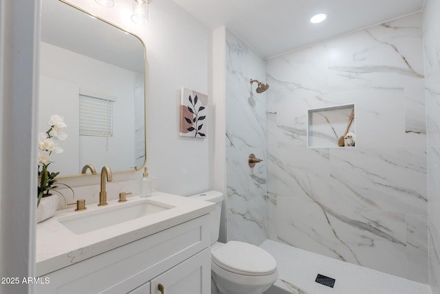 bathroom with toilet, tiled shower, and vanity