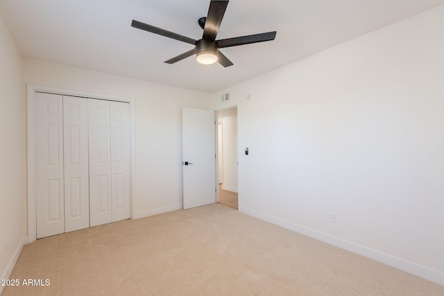 unfurnished bedroom featuring ceiling fan, a closet, and light carpet