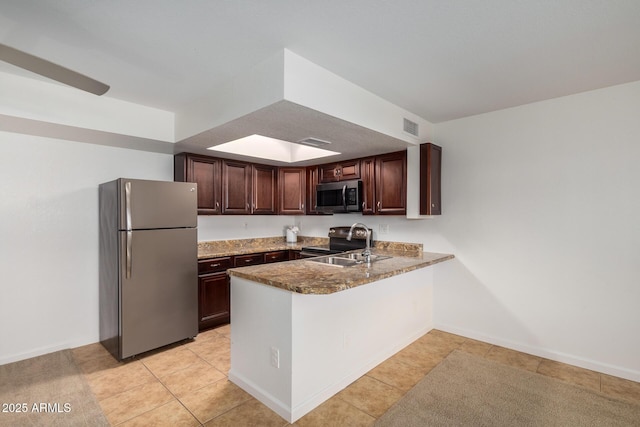 kitchen featuring appliances with stainless steel finishes, a sink, a peninsula, light tile patterned floors, and visible vents