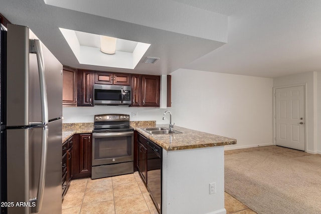 kitchen featuring a tray ceiling, a sink, light tile patterned floors, a peninsula, and stainless steel appliances