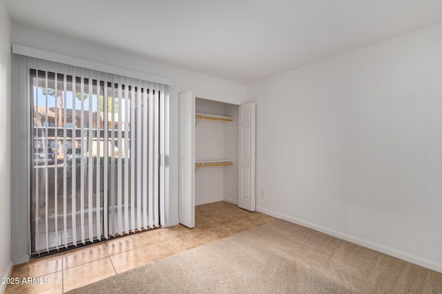 unfurnished bedroom with tile patterned floors, baseboards, carpet, and a closet