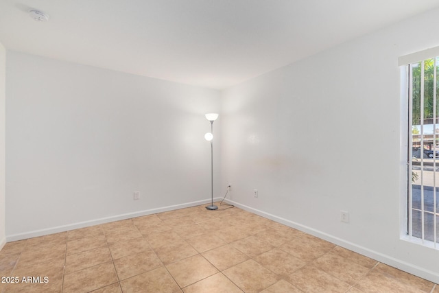 empty room with light tile patterned floors and baseboards