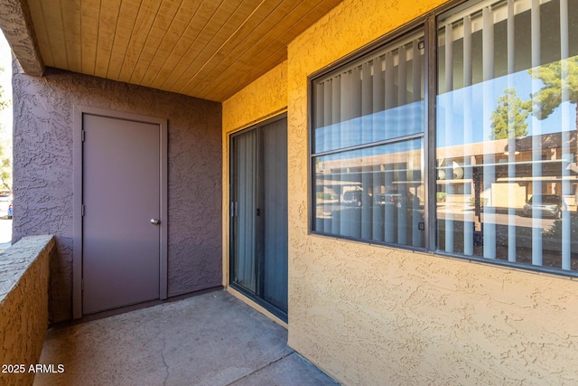 entrance to property with stucco siding and a balcony