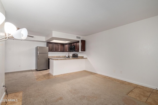 kitchen featuring visible vents, light colored carpet, dark brown cabinets, a peninsula, and stainless steel appliances