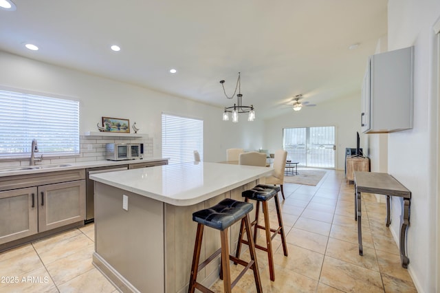 kitchen featuring sink, light tile patterned floors, hanging light fixtures, a kitchen island, and stainless steel dishwasher