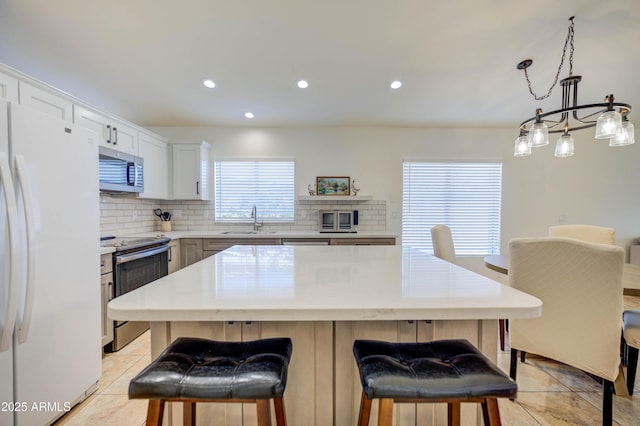 kitchen featuring a kitchen island, appliances with stainless steel finishes, sink, white cabinets, and backsplash