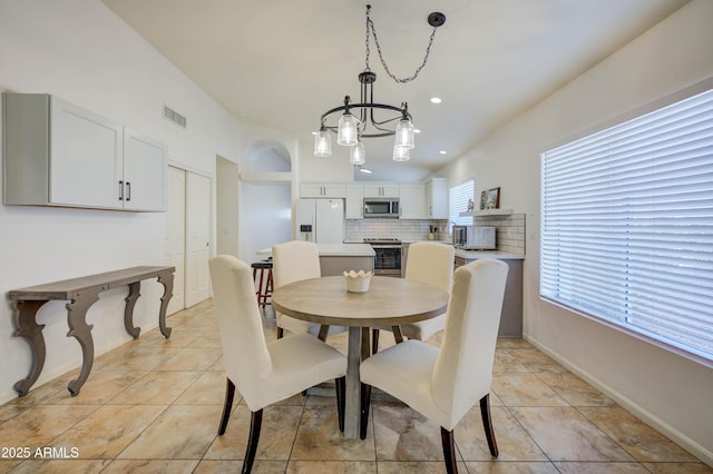 dining room featuring an inviting chandelier, vaulted ceiling, and light tile patterned flooring