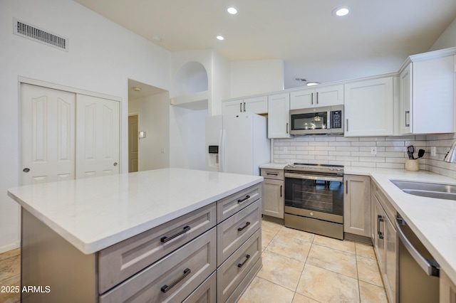 kitchen featuring decorative backsplash, appliances with stainless steel finishes, sink, and a kitchen island