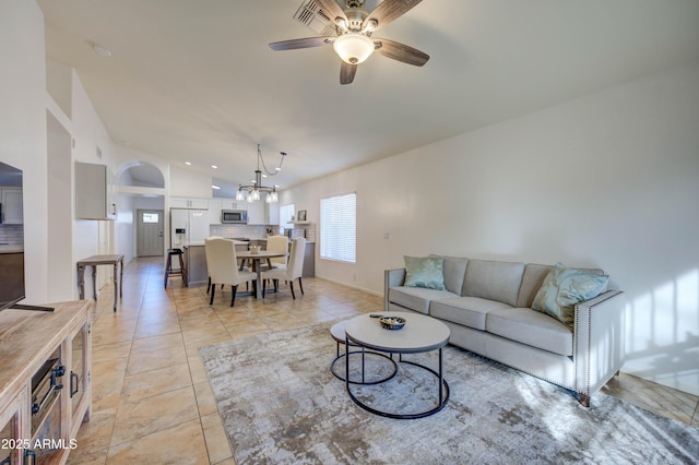 tiled living room featuring lofted ceiling and ceiling fan with notable chandelier