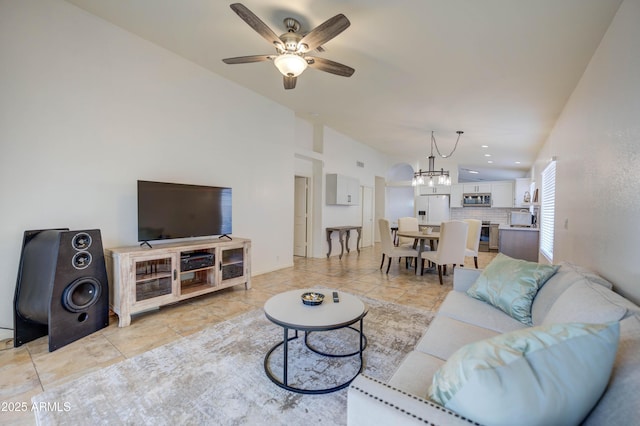 living room featuring lofted ceiling, light tile patterned floors, and ceiling fan with notable chandelier