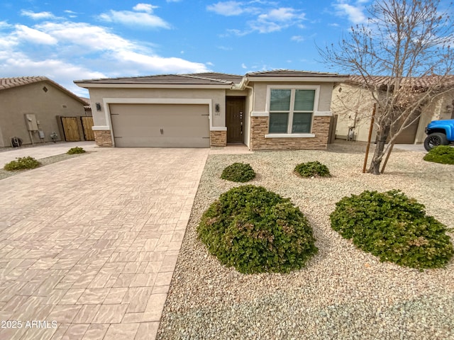 view of front facade with a garage, stone siding, a tiled roof, decorative driveway, and stucco siding