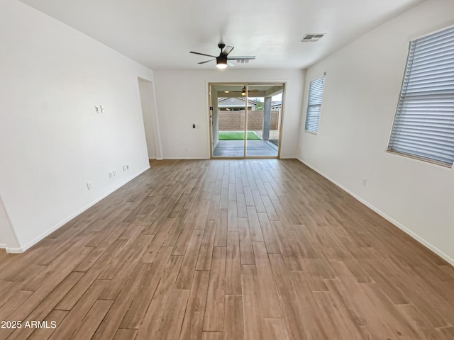 interior space featuring a ceiling fan, light wood-type flooring, visible vents, and baseboards