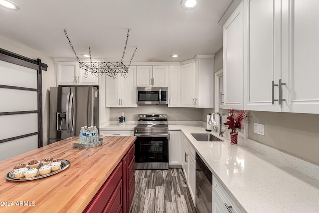 kitchen featuring wooden counters, sink, white cabinets, a barn door, and stainless steel appliances