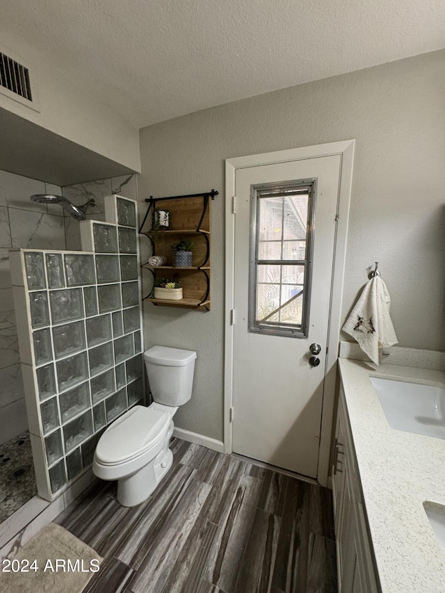 bathroom featuring vanity, hardwood / wood-style flooring, tiled shower, and a textured ceiling