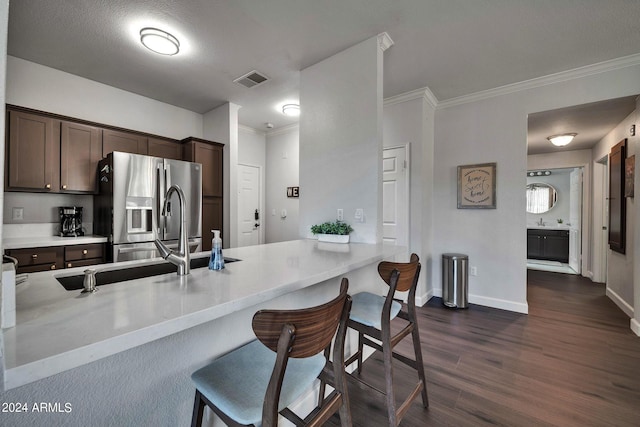 kitchen with crown molding, a breakfast bar area, stainless steel refrigerator with ice dispenser, dark brown cabinetry, and dark hardwood / wood-style flooring