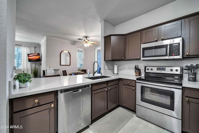 kitchen with sink, dark brown cabinets, stainless steel appliances, ornamental molding, and kitchen peninsula