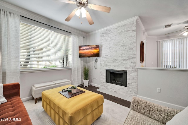 living room with ornamental molding, a stone fireplace, ceiling fan, and light hardwood / wood-style flooring