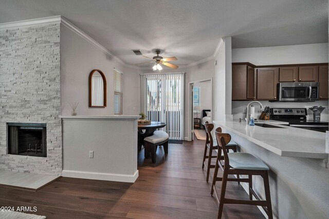 kitchen featuring sink, dark brown cabinets, ornamental molding, dark hardwood / wood-style floors, and stainless steel appliances