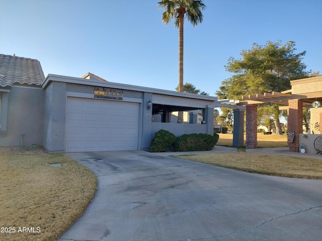 view of front facade with a garage, concrete driveway, a tiled roof, stucco siding, and a front lawn