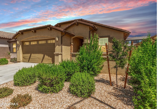 view of front of home featuring concrete driveway, an attached garage, a tiled roof, and stucco siding