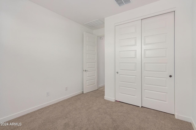 unfurnished bedroom with baseboards, a closet, visible vents, and light colored carpet