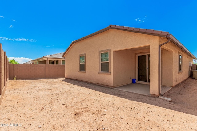 rear view of property with a fenced backyard, a patio, and stucco siding