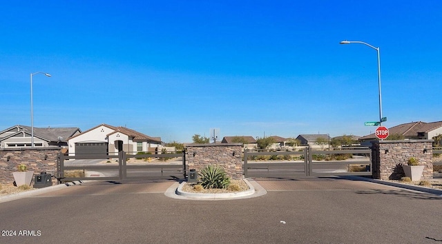 view of street featuring traffic signs, a gate, curbs, and a gated entry