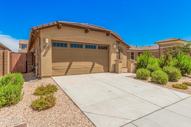 view of front of house with a garage, driveway, a tile roof, a gate, and stucco siding