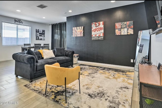 living area with recessed lighting, visible vents, baseboards, and wood finished floors