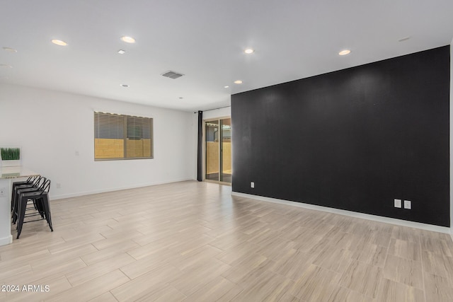 empty room with an accent wall, recessed lighting, visible vents, and baseboards