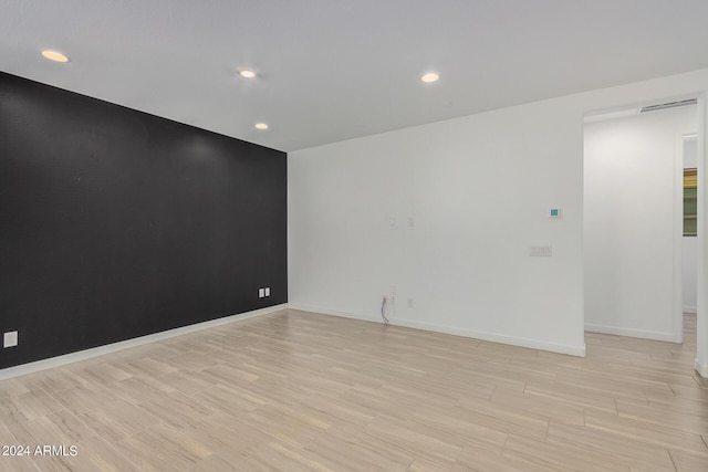 unfurnished room featuring an accent wall, recessed lighting, light wood-type flooring, and baseboards