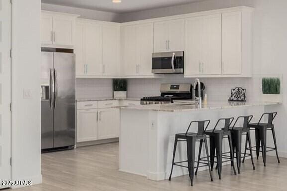 kitchen with a peninsula, appliances with stainless steel finishes, white cabinets, and decorative backsplash