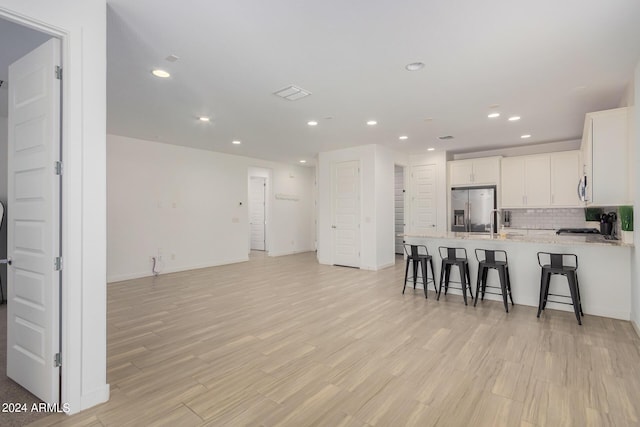 kitchen with stainless steel appliances, a breakfast bar, a peninsula, white cabinets, and backsplash