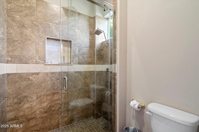 bathroom with a shower with shower door and toilet