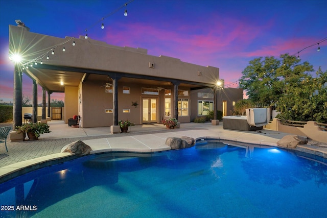 pool at dusk featuring ceiling fan, french doors, and a patio area