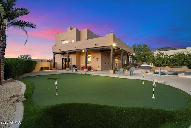 back house at dusk featuring ceiling fan and a patio