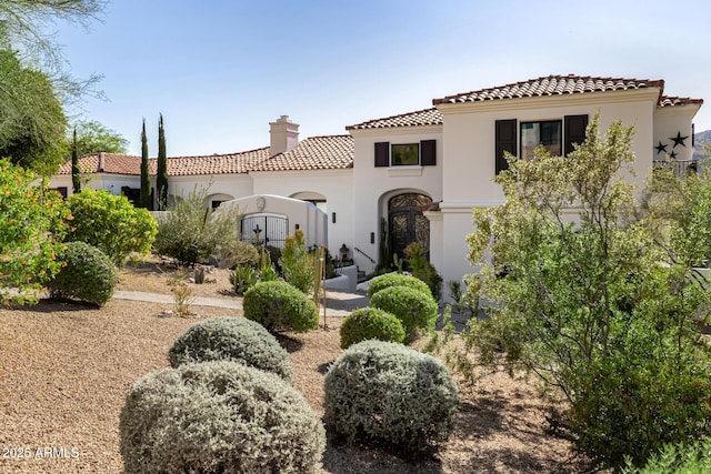 back of property featuring a chimney, a tiled roof, and stucco siding