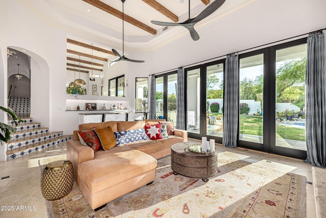 living area featuring a ceiling fan, beam ceiling, plenty of natural light, french doors, and a towering ceiling