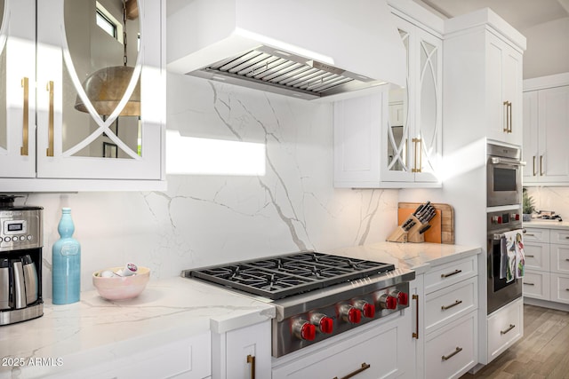kitchen with premium range hood, stainless steel appliances, backsplash, white cabinetry, and glass insert cabinets