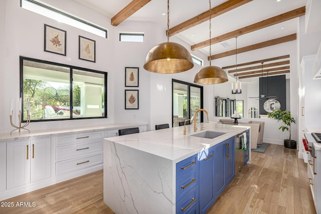 kitchen featuring blue cabinets, a sink, white cabinets, light wood-style flooring, and beamed ceiling