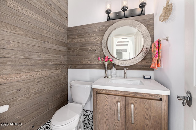 half bath with toilet, vanity, and wood walls