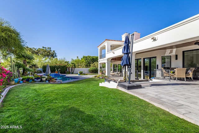view of grassy yard featuring a patio, a balcony, and outdoor dining area