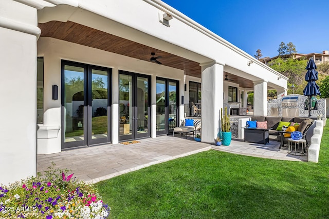 rear view of property featuring ceiling fan, outdoor lounge area, french doors, a lawn, and a patio area