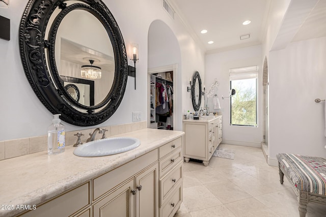 bathroom featuring tile patterned floors, two vanities, a stall shower, ornamental molding, and recessed lighting