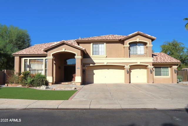 mediterranean / spanish house with concrete driveway, a balcony, stucco siding, an attached garage, and a tile roof