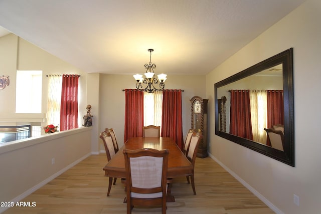 dining area with light wood-style flooring, an inviting chandelier, and baseboards