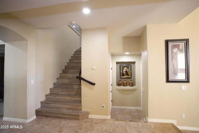 staircase featuring baseboards, recessed lighting, and arched walkways