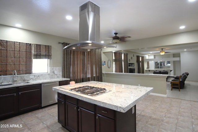 kitchen with a ceiling fan, a kitchen island, island exhaust hood, a sink, and stainless steel appliances