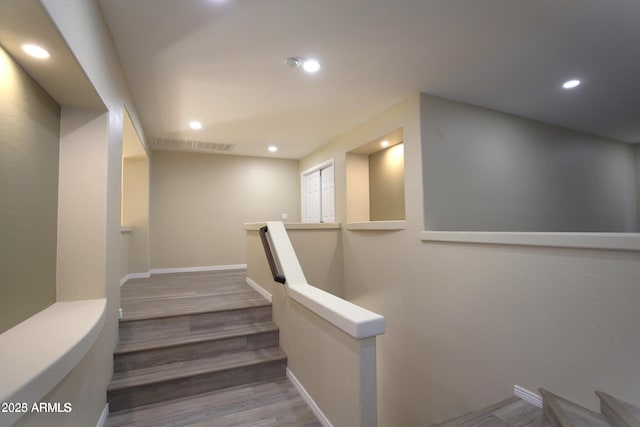 stairs featuring wood finished floors, baseboards, visible vents, and recessed lighting