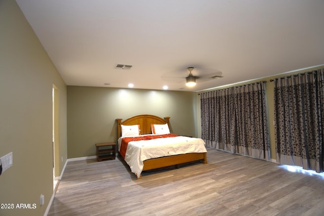 bedroom featuring visible vents, baseboards, a ceiling fan, and wood finished floors